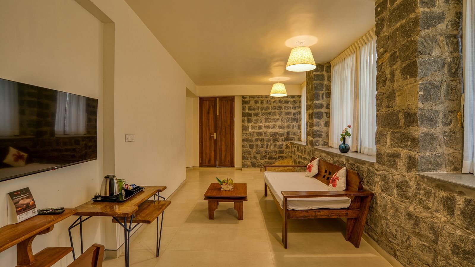 Living room with stone walls, comfortable seating, and a flat-screen TV. | Mango Hill, Yercaud