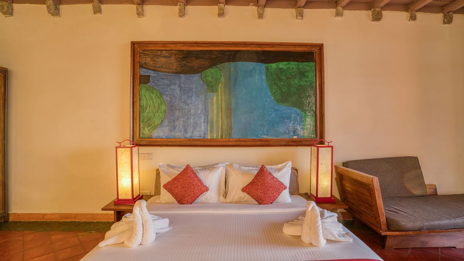 Comfortable bedroom with a king-size bed, colorful artwork, wooden furniture, and ample natural light, creating a warm and inviting atmosphere. | Mango Hill, Yercaud