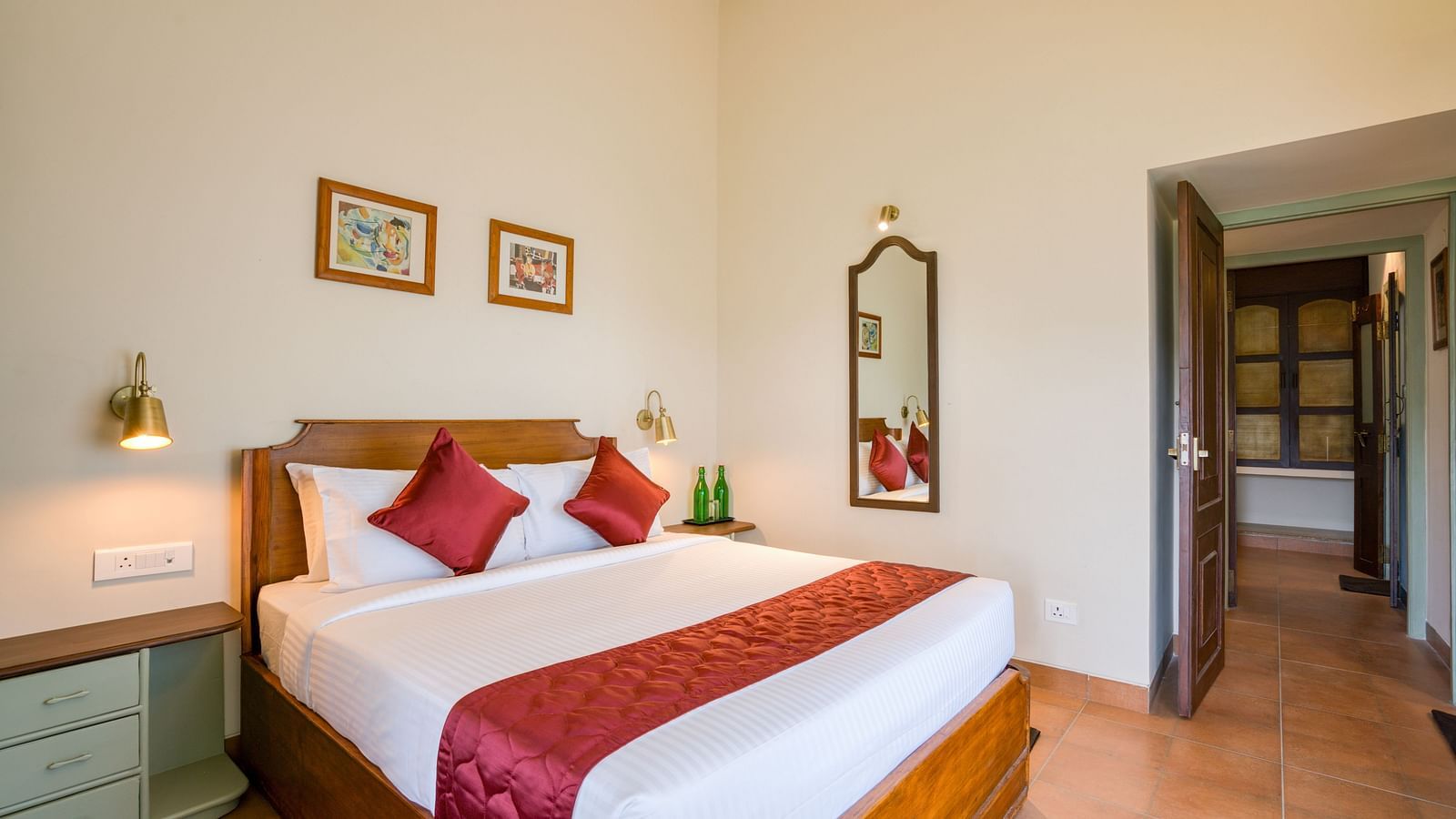 A double bed with red pillows and runner inside bedroom villa with a balcony | Mango Hill Shola Ooty