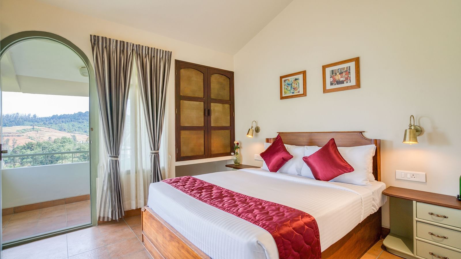 A double bed with red pillows and runner inside bedroom villa with a balcony | Mango Hill Shola Ooty