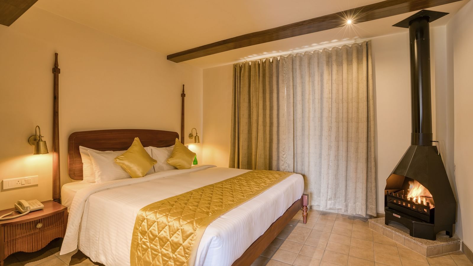 A double bed with a fireplace in the corner inside junior suite | Mango Hill Shola Ooty