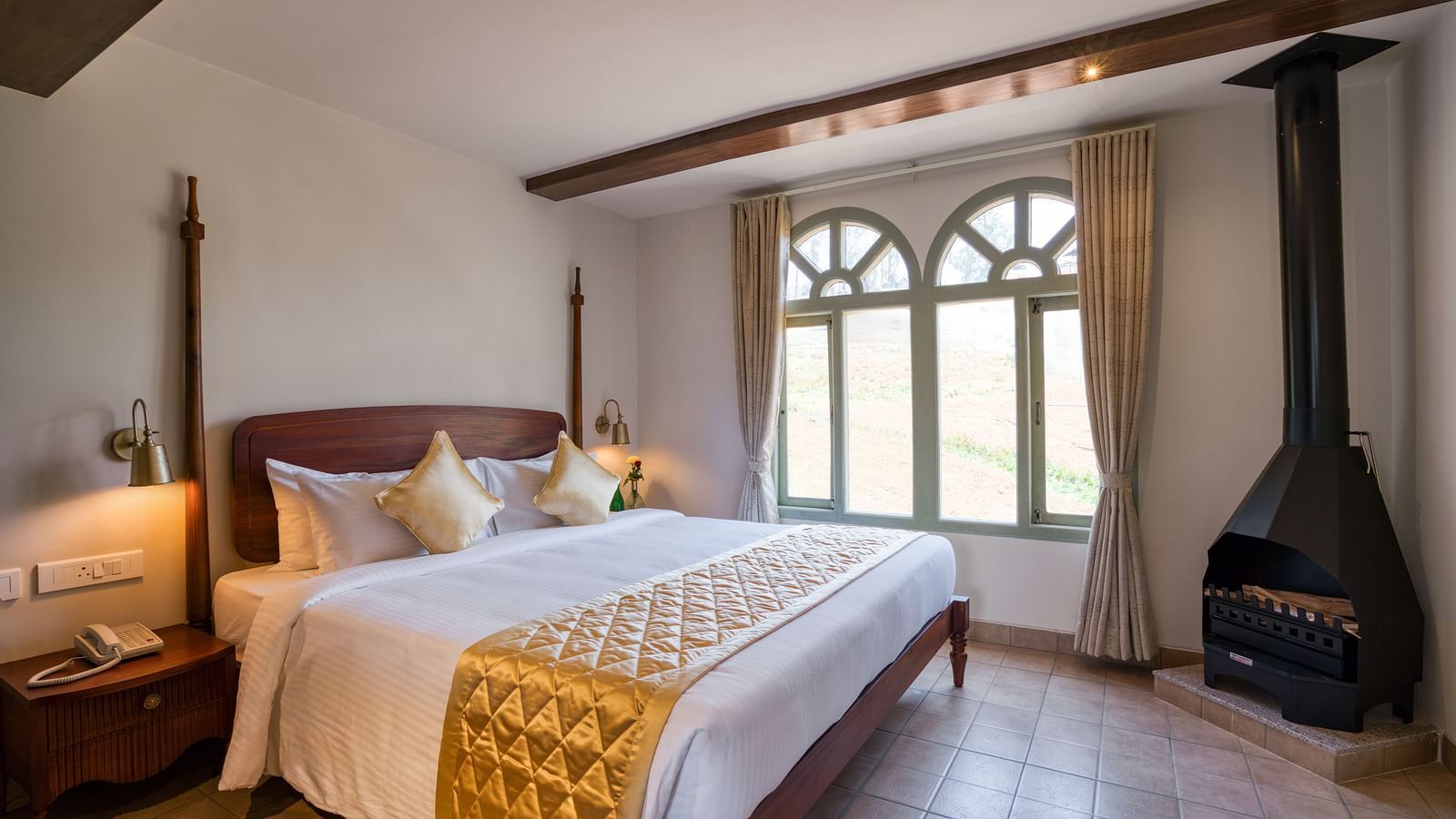 A double bed with a fireplace in the corner inside junior suite | Mango Hill Shola Ooty