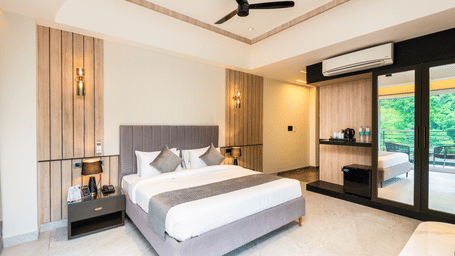 Spacious bedroom with balcony  and king bed at DLS Divine River Resort & Spa, Rishikesh.