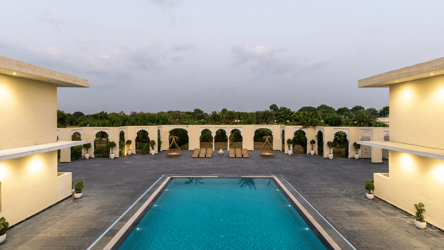 Exterior of Beelwa Palace, featuring a large swimming pool set against a cloudy backdrop.