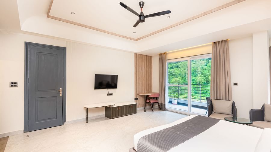 Overview of Premium Room at DLS Divine River Resort and  Spa featuring a  king bed, table, chair and balcony with forest views.