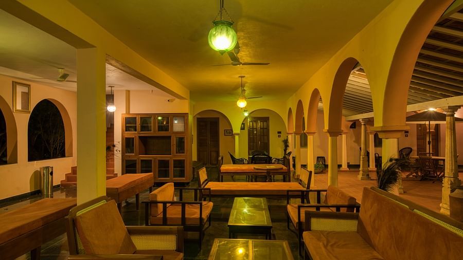 Dinning space in a corridor at resort with chairs and tables during night time.