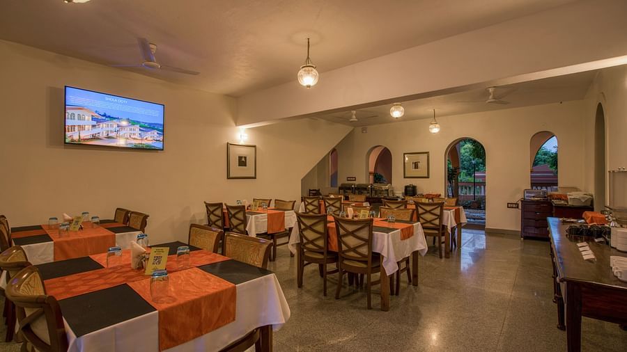 Dinning space with chairs and tables and a TV hanging on the wall.