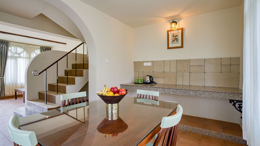 The dining area in view with a staircase on the side inside bedroom villa with a balcony | Mango Hill Shola Ooty