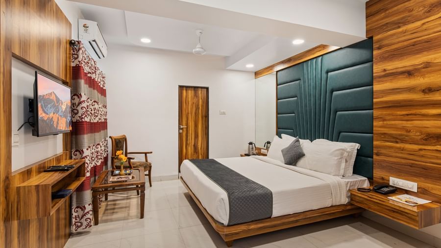 Modern room at Mayur Retreat with green accent wall, large bed, and coordinated dining area.
