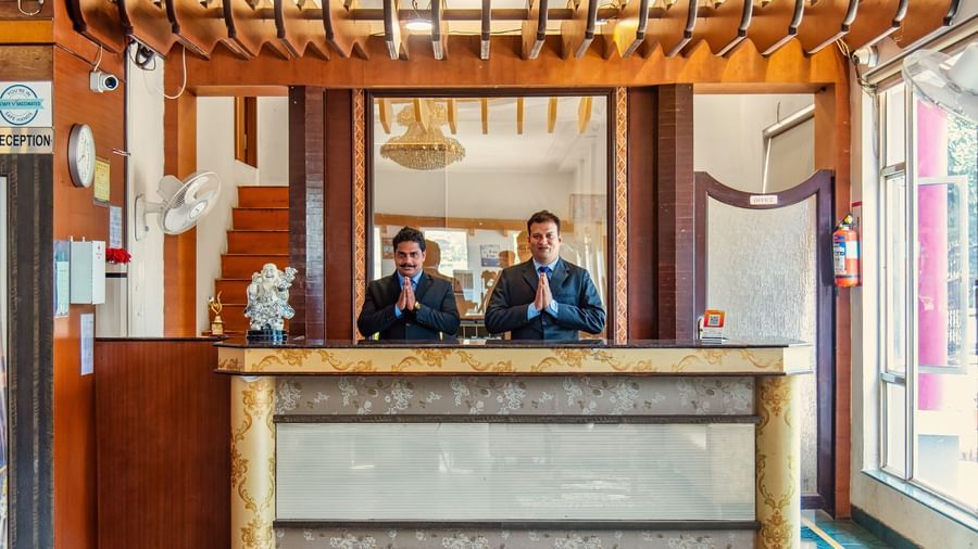 2 resort workers welcoming the guests at the reception desk of Mayur Retreat.