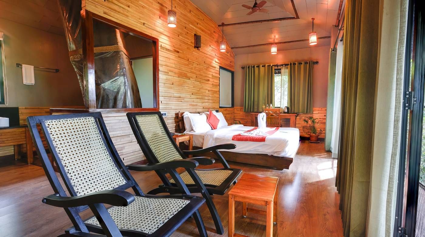 Two chairs and a bed in a room | Vythiri Resort. Wayanad
