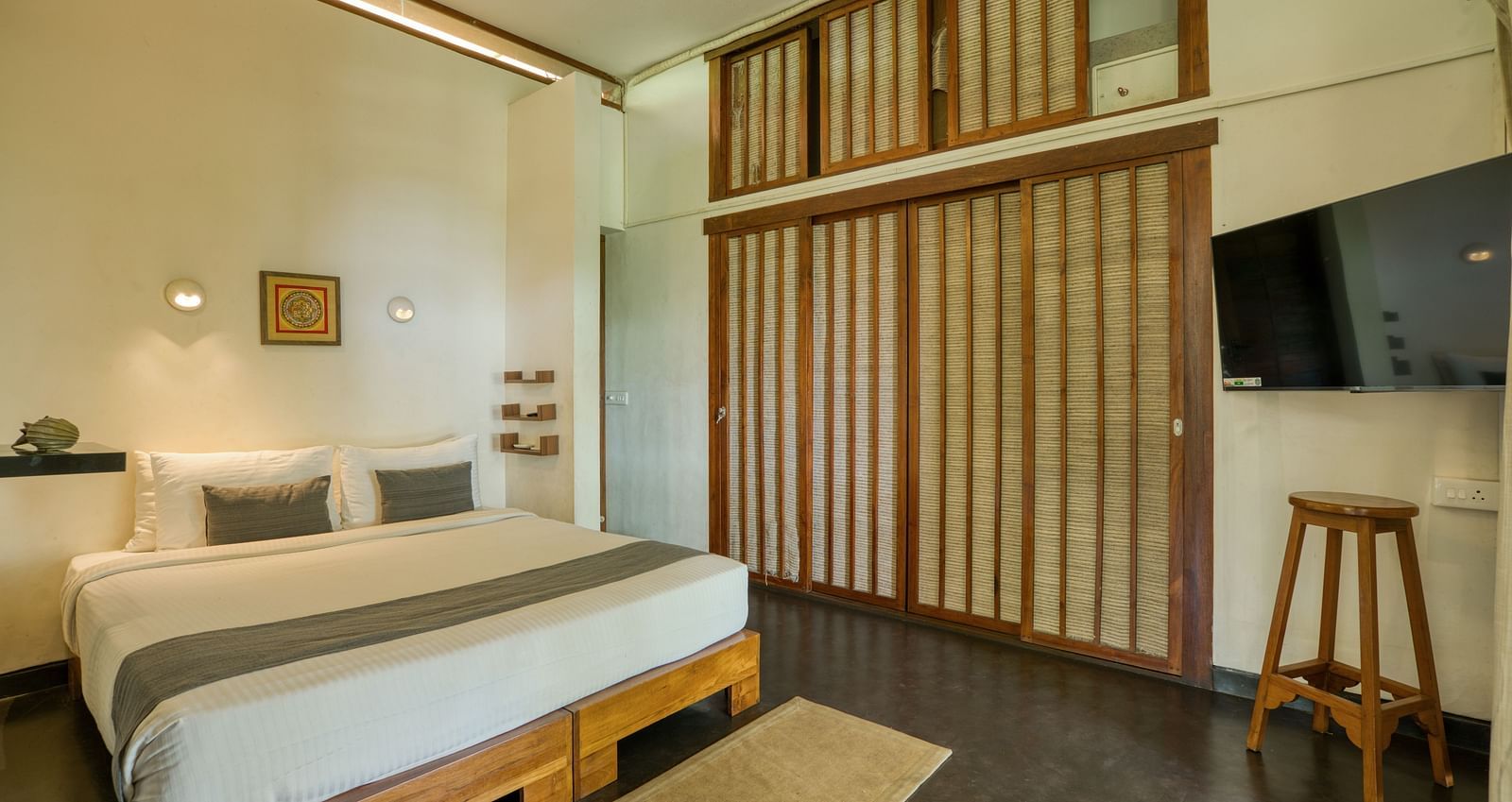 Villa room with a flat screen television, and soft white lights for reading above the bed.