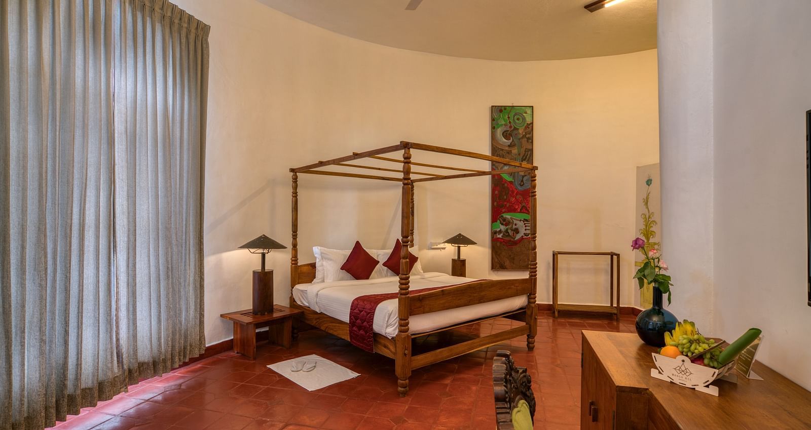 A suite with four-poster bed, large window beside it and a table at the corner | Mango Hill, Yercaud