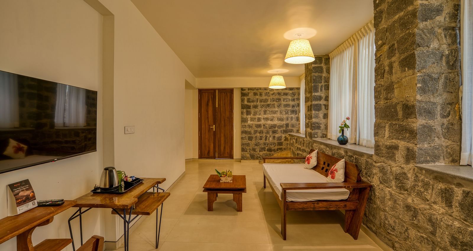 Living room with stone walls, comfortable seating, and a flat-screen TV. | Mango Hill, Yercaud
