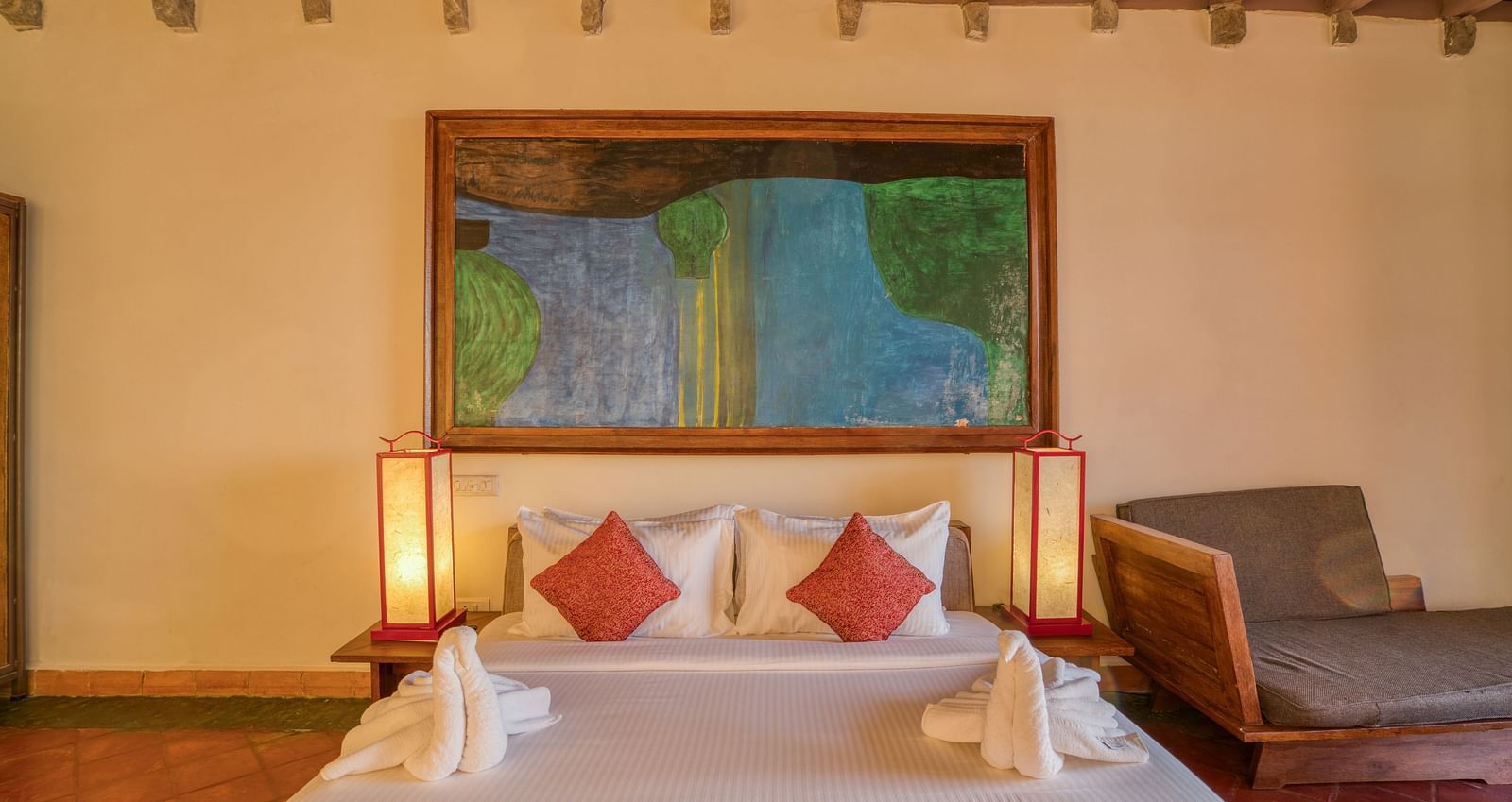 Comfortable bedroom with a king-size bed, colorful artwork, wooden furniture, and ample natural light, creating a warm and inviting atmosphere. | Mango Hill, Yercaud