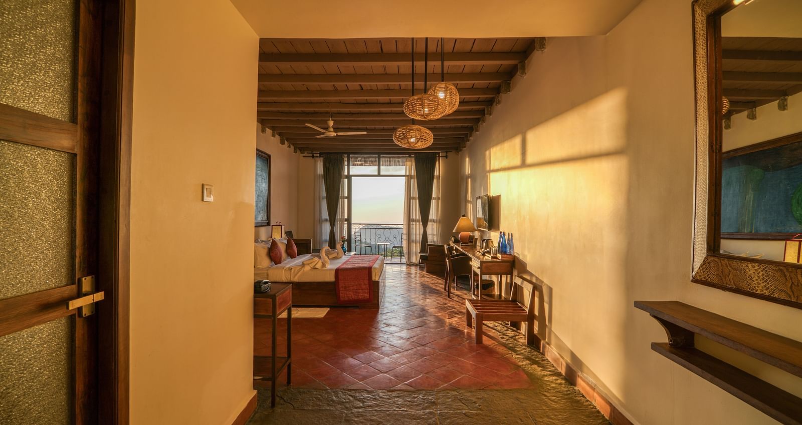 Warmly lit corridor with wooden ceiling beams and sunlight streaming through the windows at a mountain resort.  | Mango Hill, Yercaud