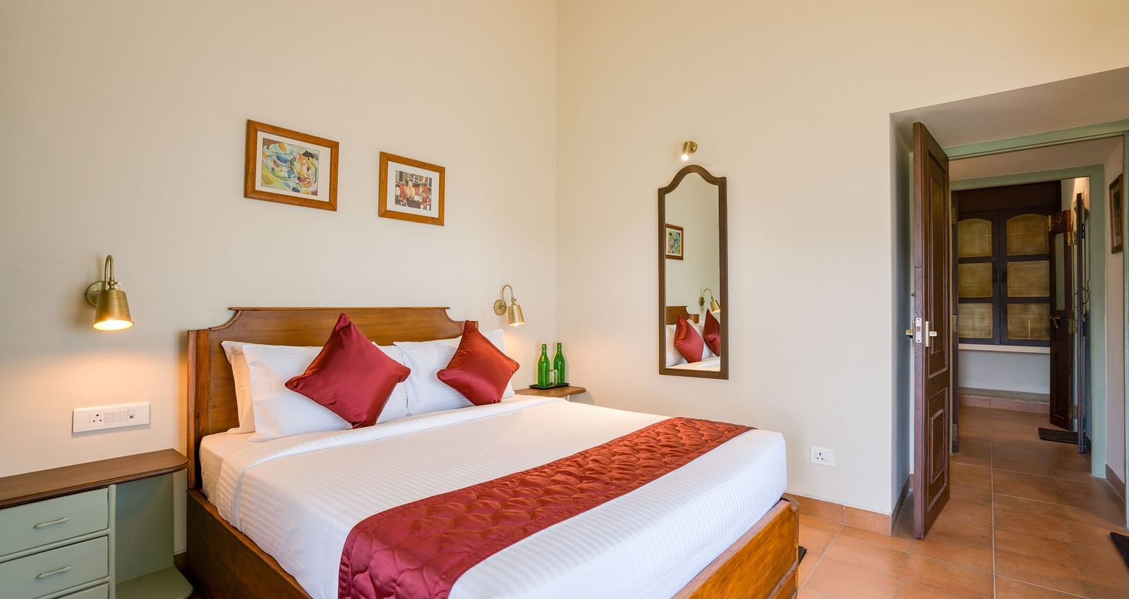 A double bed with red pillows and runner inside bedroom villa with a balcony | Mango Hill Shola Ooty