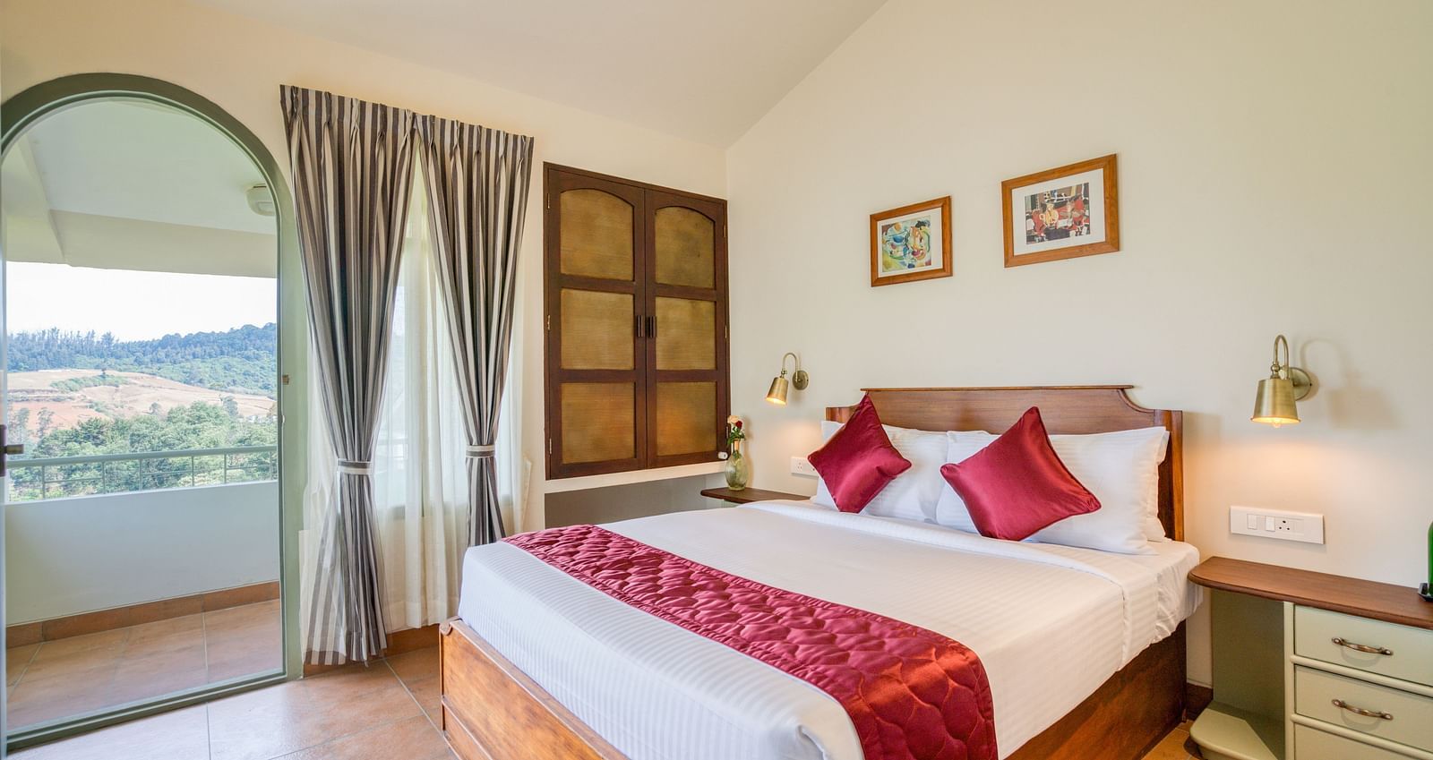A double bed with red pillows and runner inside bedroom villa with a balcony | Mango Hill Shola Ooty