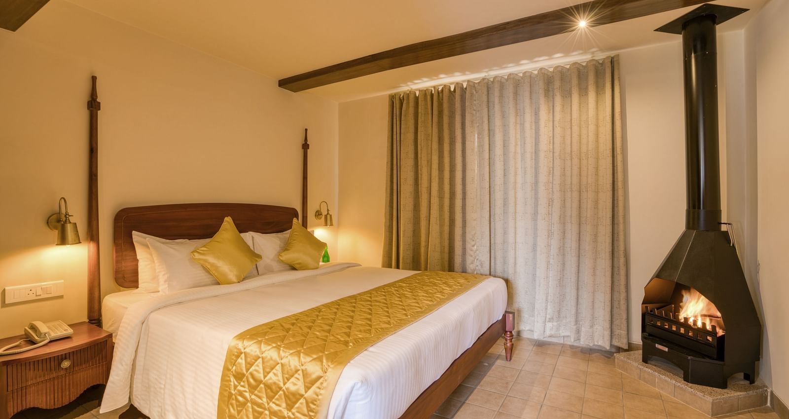 A double bed with a fireplace in the corner inside junior suite | Mango Hill Shola Ooty