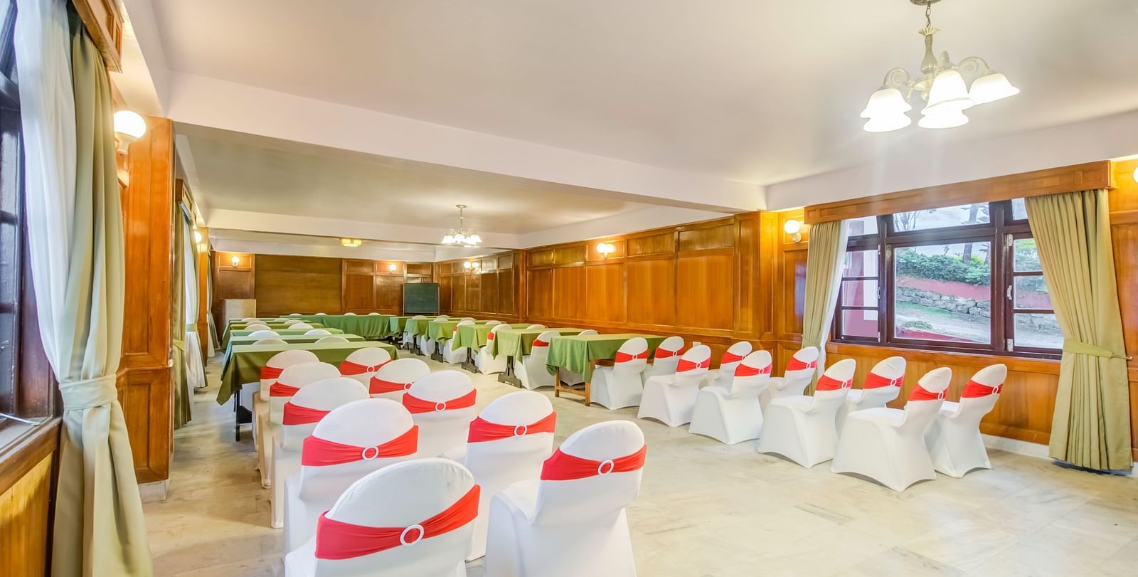 A shot of an banquet hall with white and red chairs facing the podium.