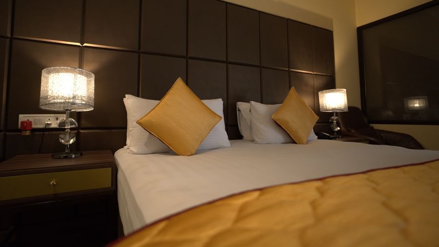 Deluxe Garden View Room at Citrus Classic Resorts and Spa Mahabalipuram ECR featuring a plush bed with fresh linen and pillows with cushions and lamps lit on both sides