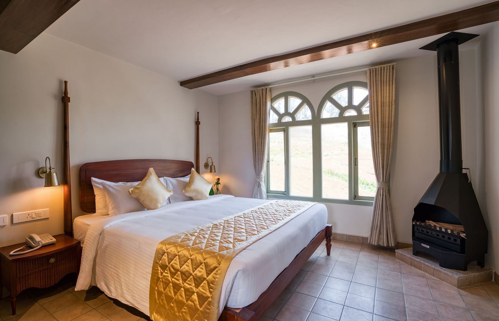 A double bed with a fireplace in the corner inside junior suite | Mango Hill Shola Ooty