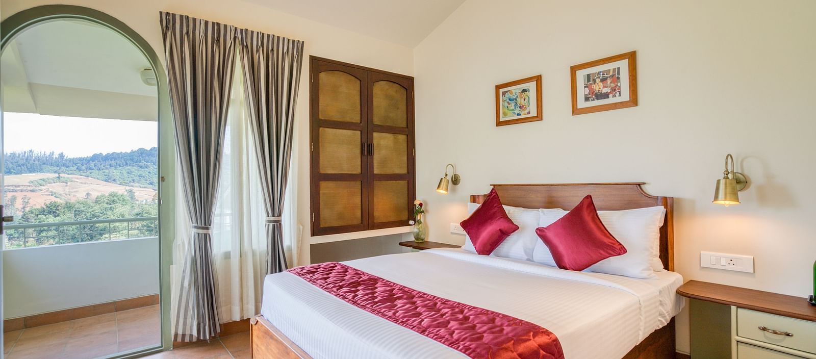 A double bed with red pillows and runner inside bedroom villa with a balcony | Mango Hill Shola Ooty