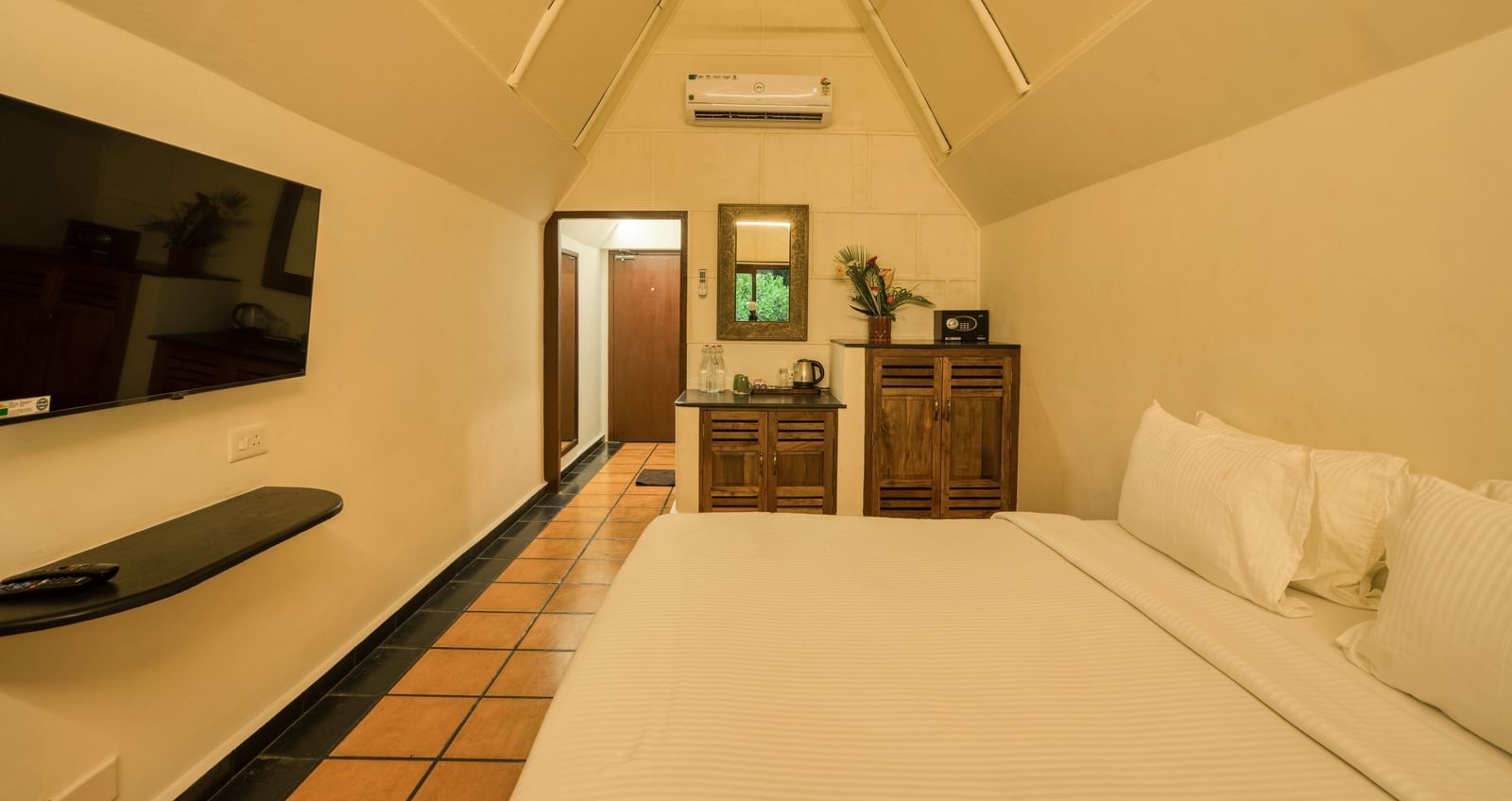 Thai Cottage Bedroom with a bed, TV and side table.