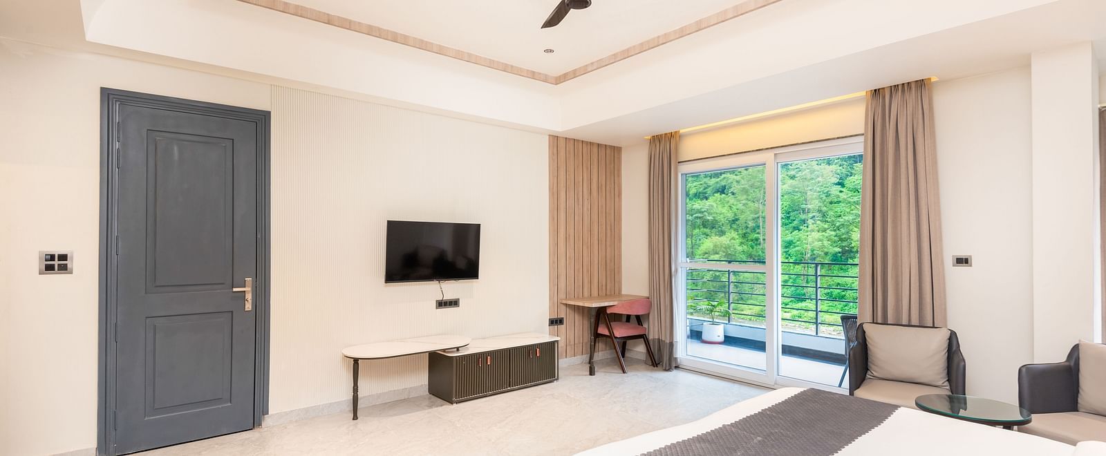 Overview of Premium Room at DLS Divine River Resort and  Spa featuring a  king bed, table, chair and balcony with forest views.