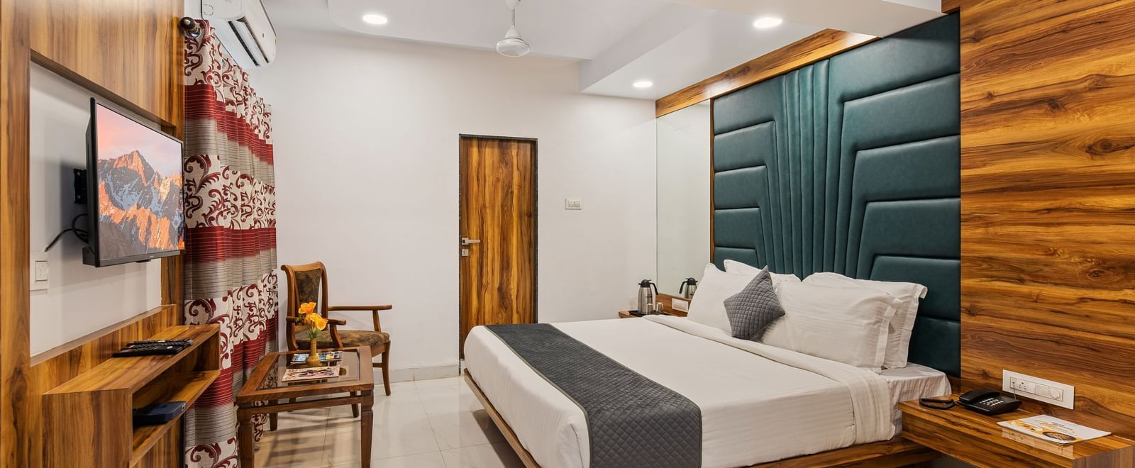 Modern room at Mayur Retreat with green accent wall, large bed, and coordinated dining area.