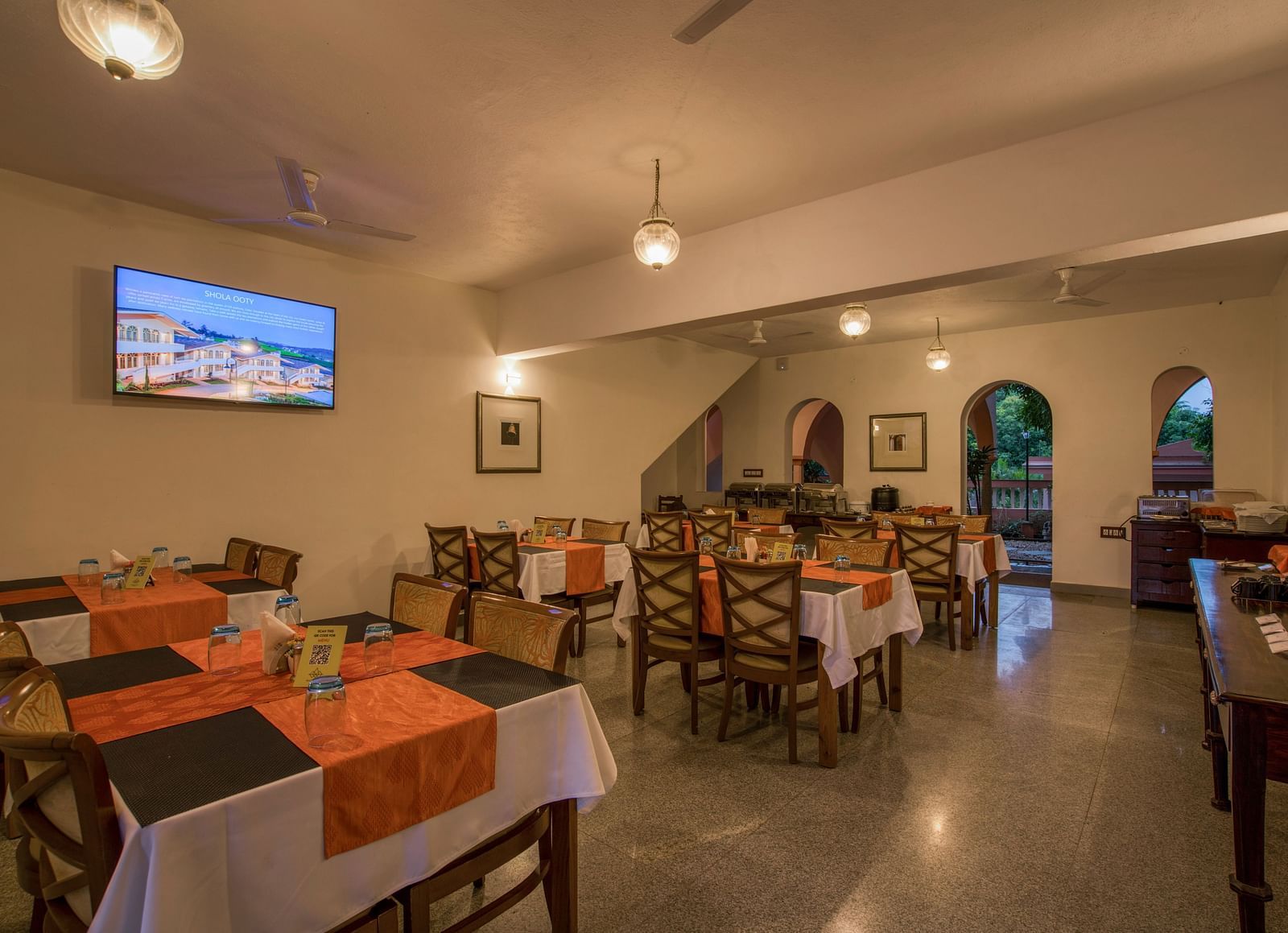 Dinning space with chairs and tables and a TV hanging on the wall.