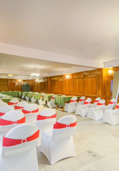 A shot of an banquet hall with white and red chairs facing the podium.
