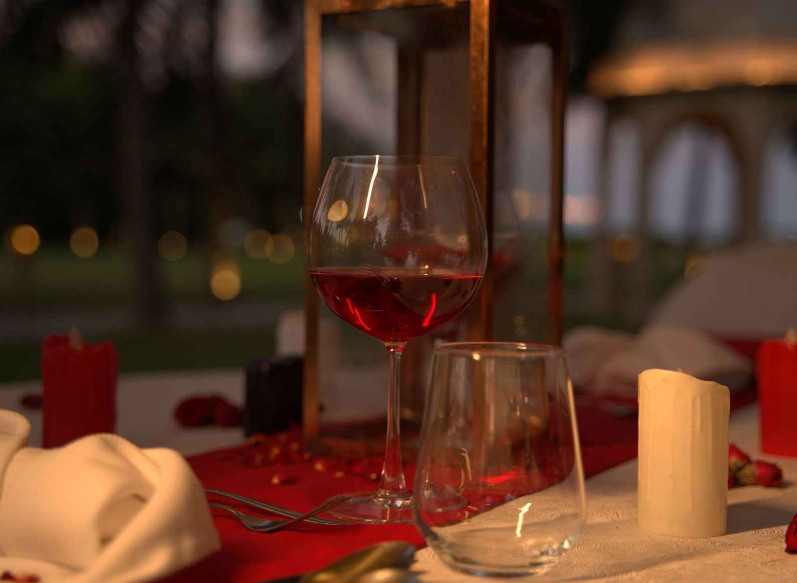 A close-up of a wine glass and candle on a red-themed dinner table - Kaldan Samudhra Palace