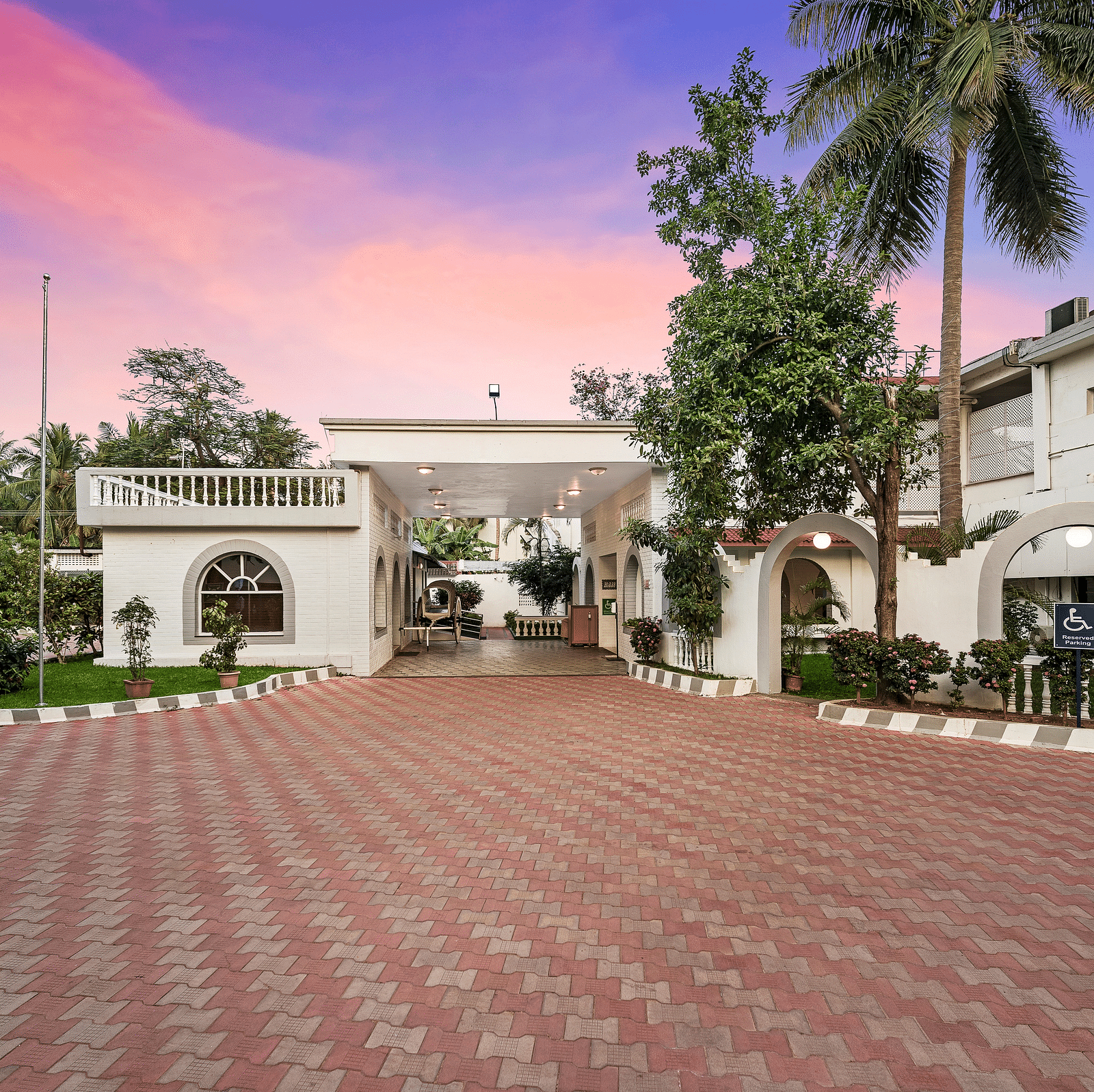 A facade image of GReaT Trails River View Resort Thanjavur By GRT Hotels with the hotel building and greenery around