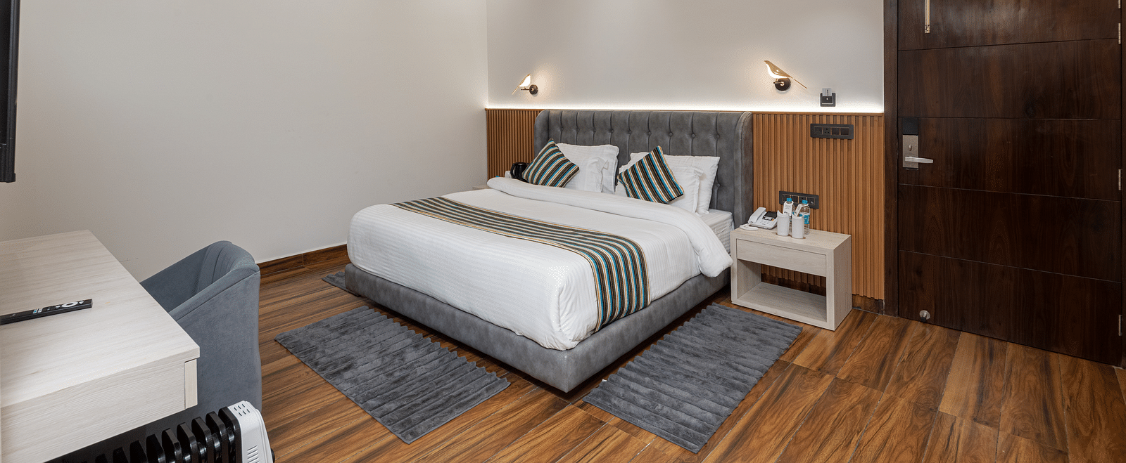 The deluxe room with a bed, bed side table, a chair, a work desk, and warm lighting - DLS The Emerald, Nainital
