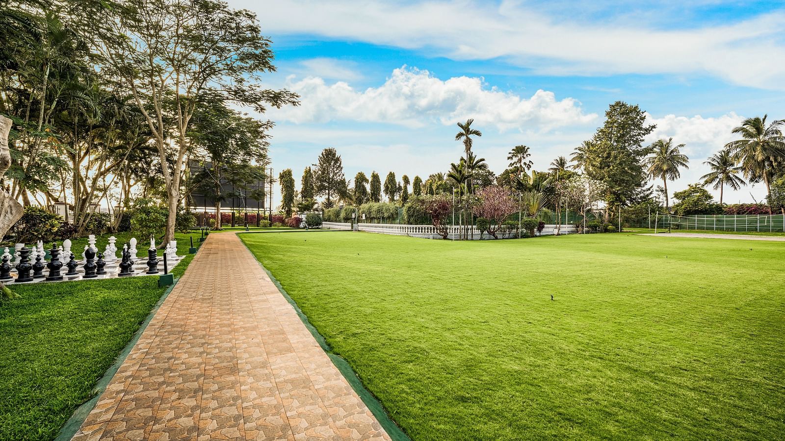 A facade image of the Vannam event space with a green lawn and greenery around - GReaT Trails River View Resort Thanjavur By GRT Hotels