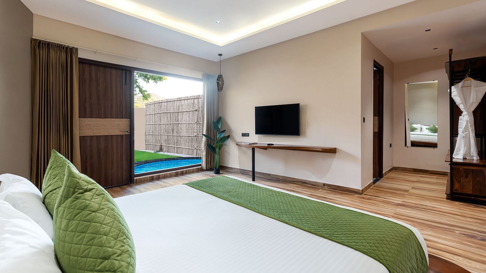 Luxury Villa with Plunge Pool featuring a king size bed with green accents, a television, and a glimpse of the bathroom at The Qualia Resort Club & Brewery, Udaipur.