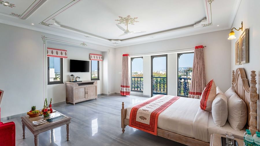 An overview of the suite with a king bed, side tables, coffee table and balcony at Maan Vilas Suite - Maan Vilas by Stone Wood, Udaipur