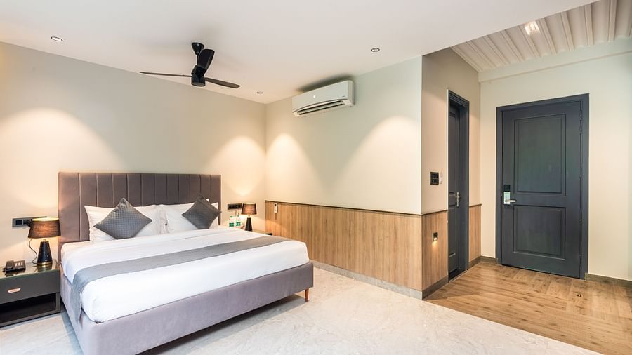 Deluxe Room at DLS Divine River Resort and  Spa featuring a  king bed , side table, warm lighting and a bathroom door.