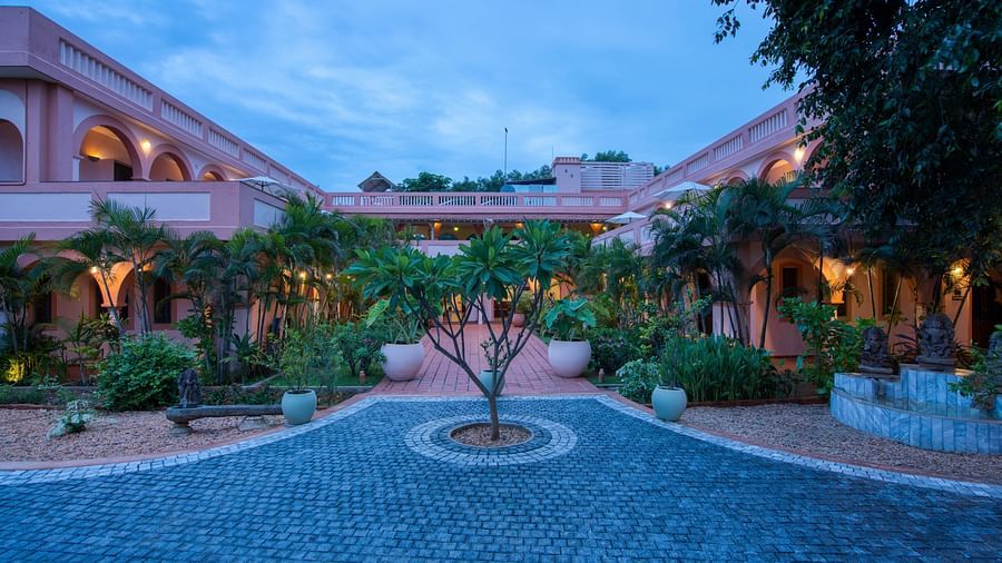 Pathway of a resort with a tree in the middle of it and a backdrop of sky with clouds.