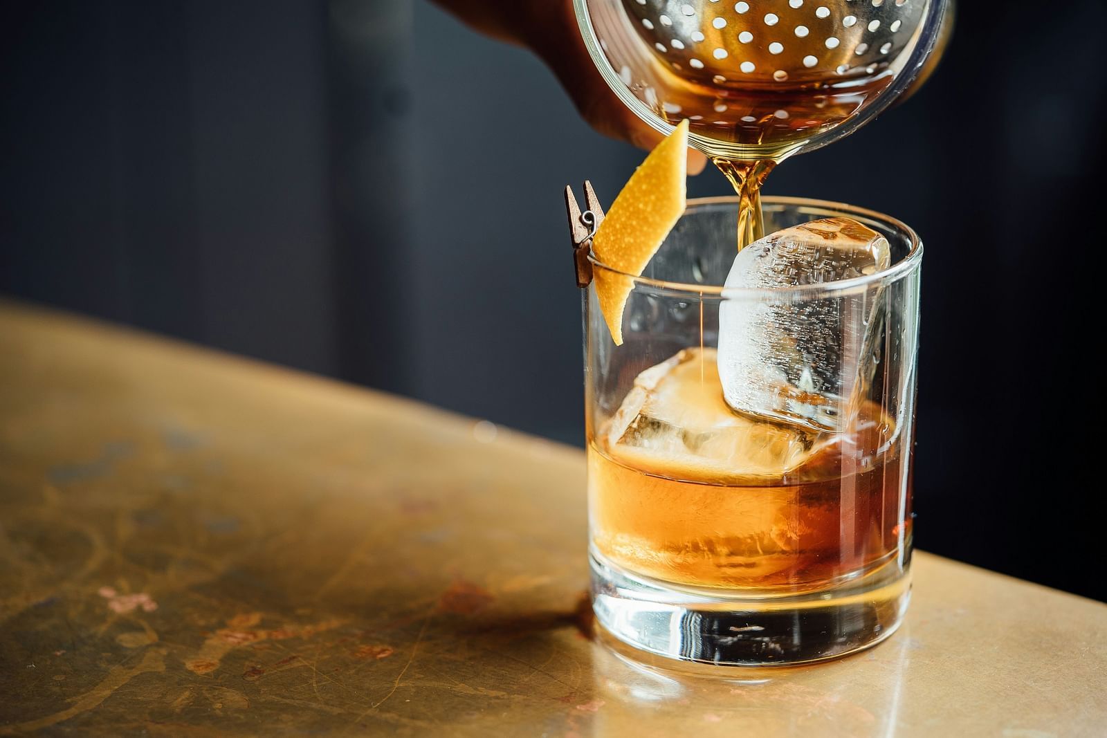 A drink being poured to a glass with ice inside it