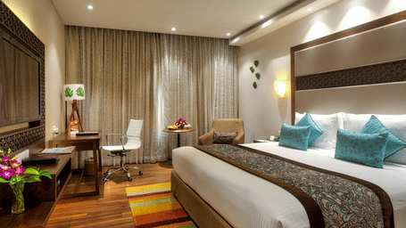 Serene Room with king size bed, chair, lamp and vase at Grand Chennai By GRT Hotels.