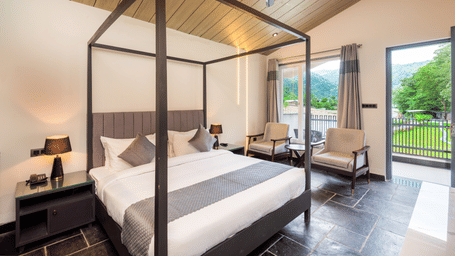 Luxury Cottage at DLS Divine Resort and Spa, Rishikesh, featuring a bed, chairs and a private balcony with garden views. 