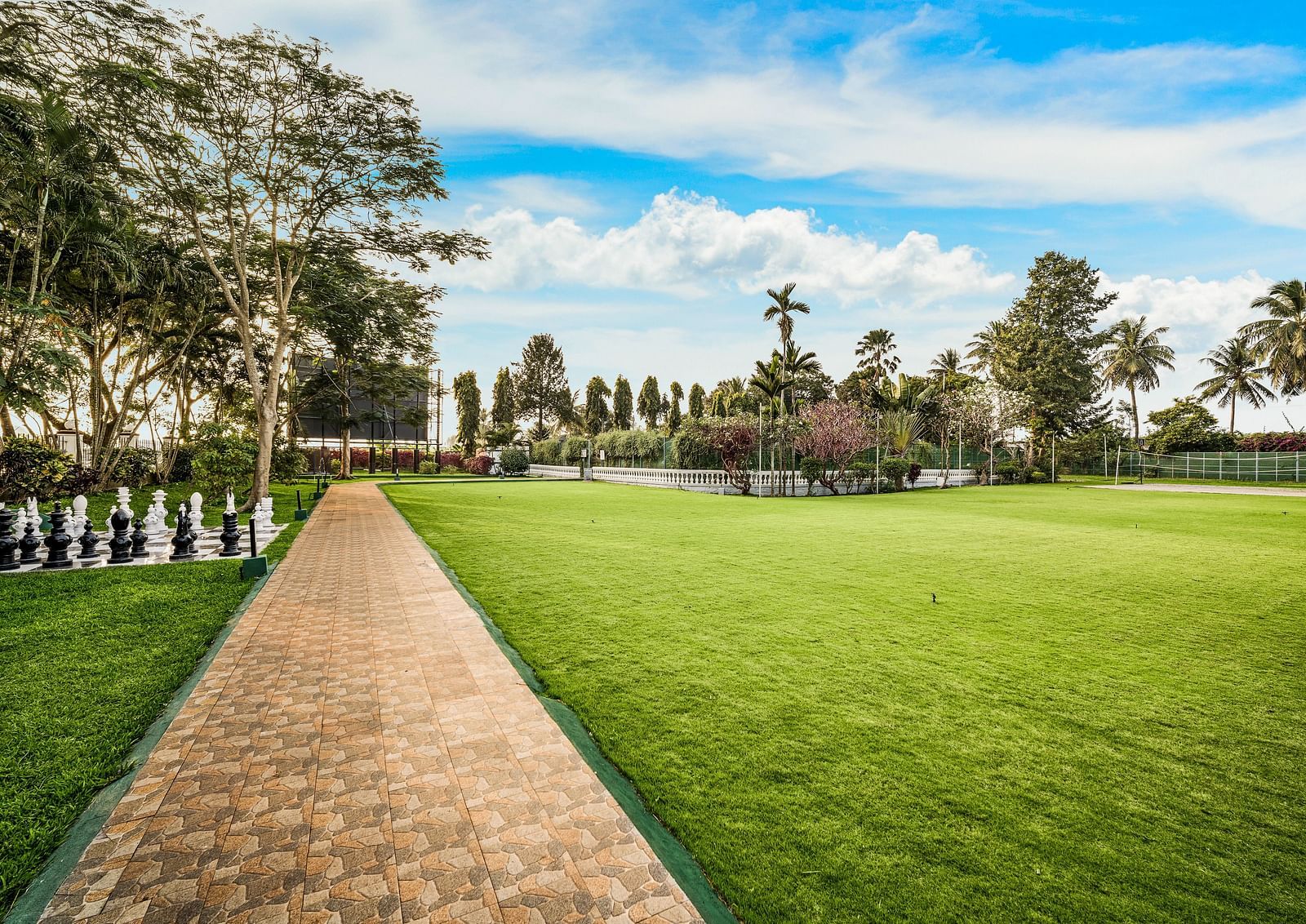A facade image of the Vannam event space with a green lawn and greenery around - GReaT Trails River View Resort Thanjavur By GRT Hotels