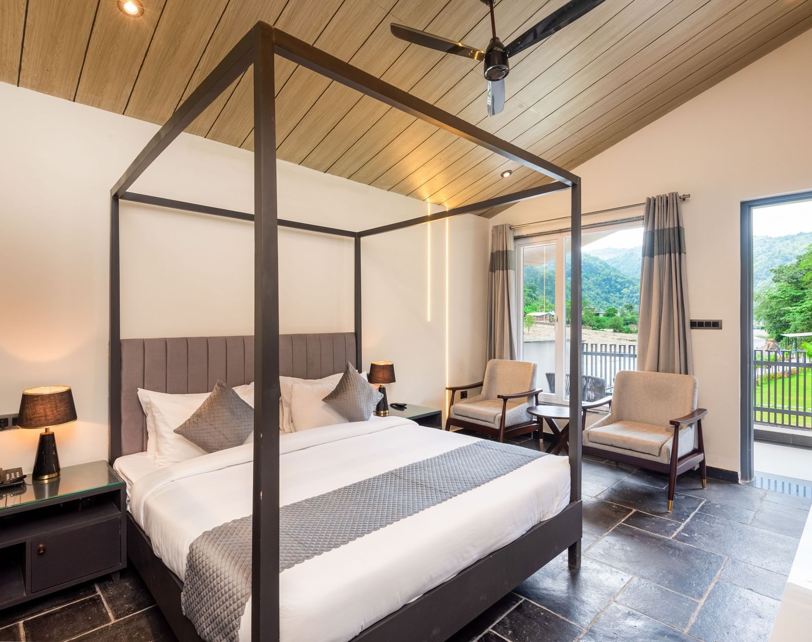 Luxury Cottage at DLS Divine Resort and Spa featuring a bed, chairs and a private balcony with garden views. 
