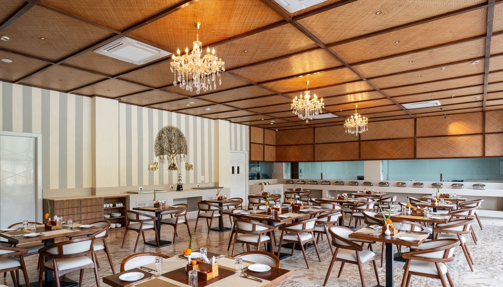 A large restaurant at Osian Valley Resort & Spa featuring a grid of wooden tables and chairs with white cushions. 