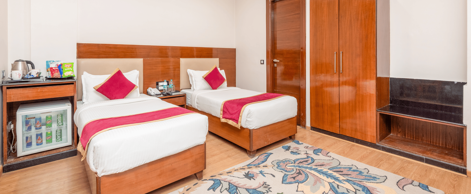 Twin bed room with wardrobe and seating at DLS Hotels On The Ganges.
