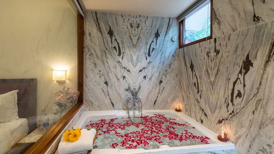 an image featuring a full size bathtub with rose petals floating on the bathtub at the the luxury suite villa at aranya vilas