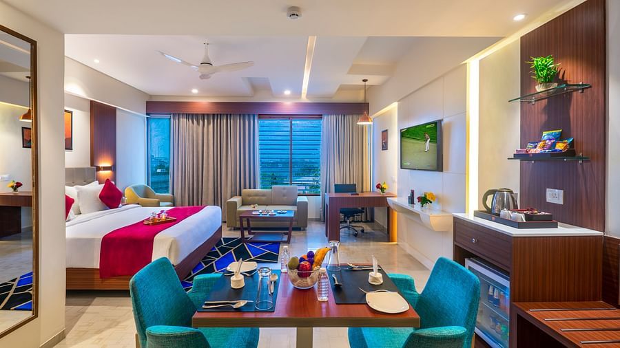 Dining space with tables set for guests and a view extending towards the balcony - Lords Eco Inn Shapar Rajkot