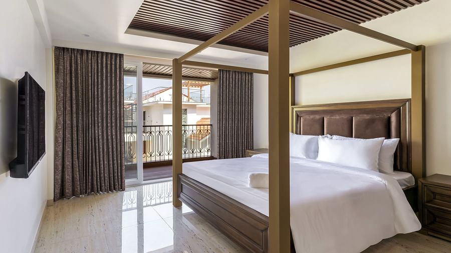 A double bed with wooden beams inside one of the rooms - The Tanisi Hotels & Resorts, Goa